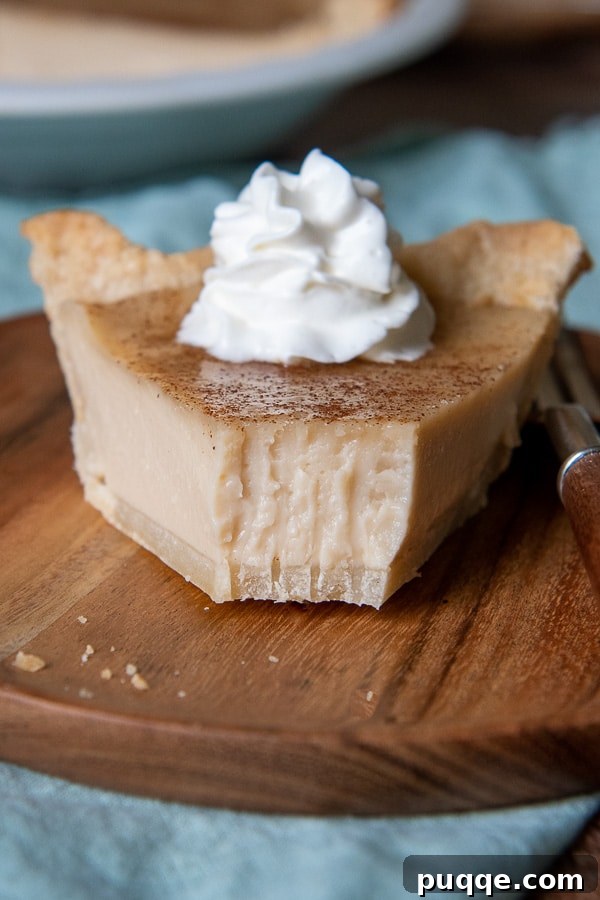 A close-up of a slice of Indiana sugar cream pie on a plate with a bite taken out, highlighting its creamy texture.