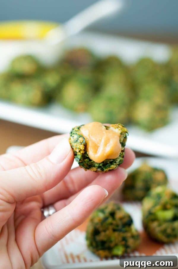 Gluten-free spinach balls alongside a bowl of hot sweet mustard dipping sauce, an ideal appetizer for any gathering.