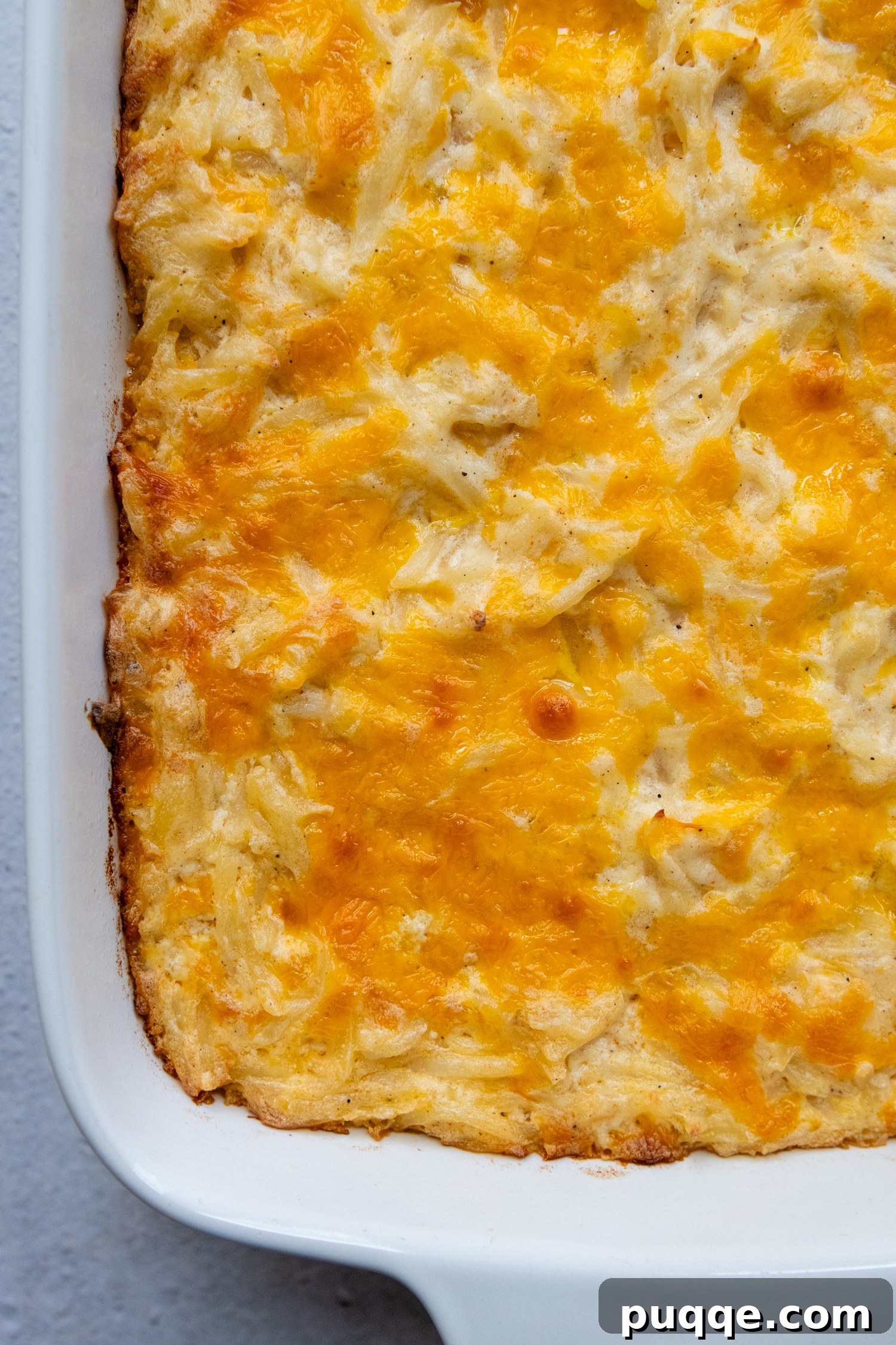 Golden, cheesy gluten-free hash brown casserole in a white baking dish, ready to be served.
