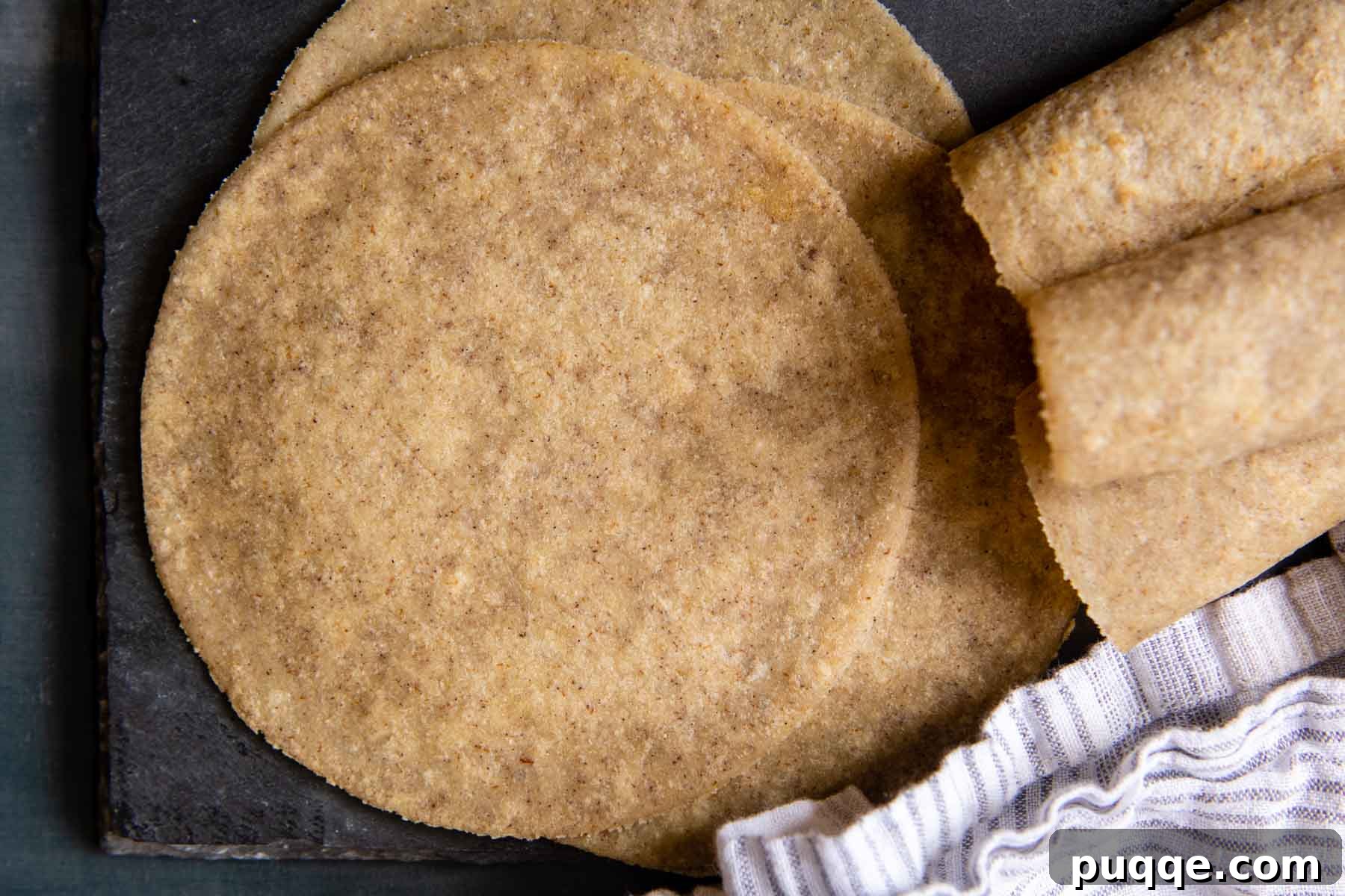 A beautiful display of both unrolled and rolled almond flour tortillas on a dark rustic surface.