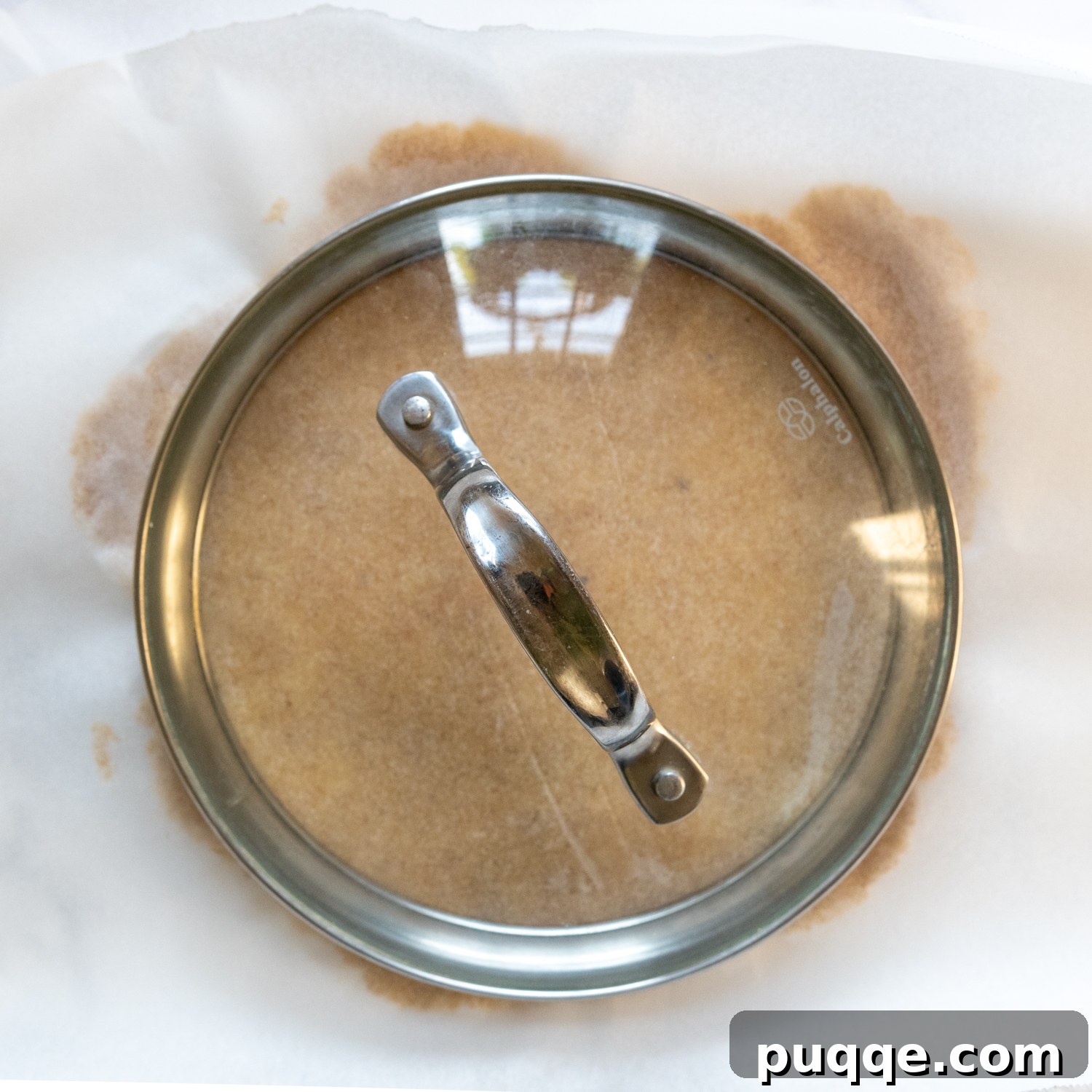 A 6-inch lid placed over the rolled tortilla on parchment paper, used for precise shaping.