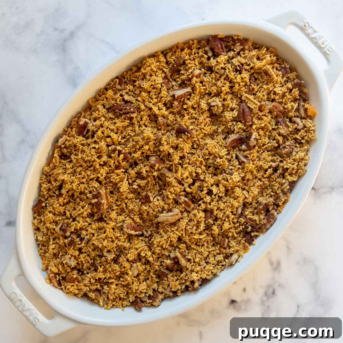 A baking dish filled with sweet potato mixture, topped with the crunchy cereal topping, ready for baking.