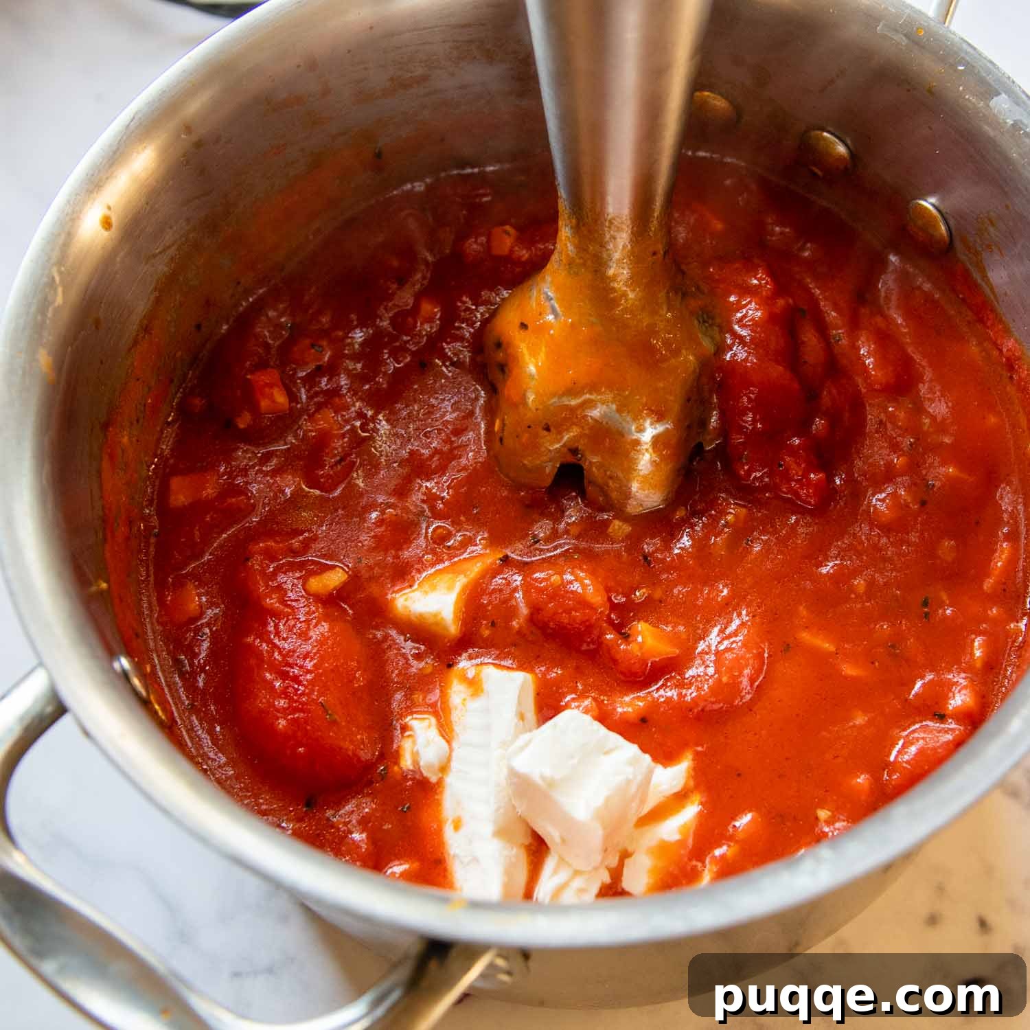 Amazing Gluten-Free Tomato Soup From Your Pantry 5 An immersion blender pureeing the tomato soup with cream cheese in the pot.