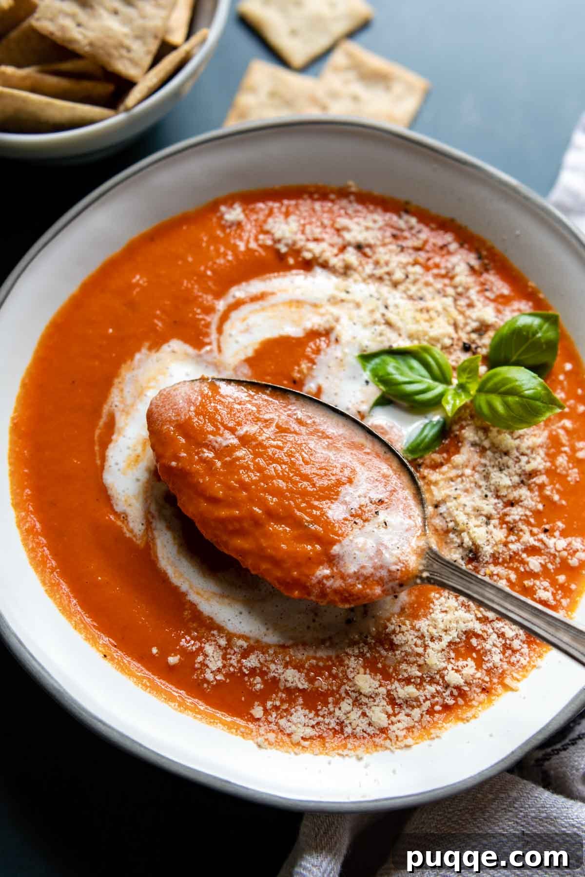 Amazing Gluten-Free Tomato Soup From Your Pantry 7 A spoon lifting a creamy dollop of tomato soup from a bowl, showcasing its rich texture.