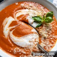 A spoon going into a bowl of creamy gluten-free tomato soup.