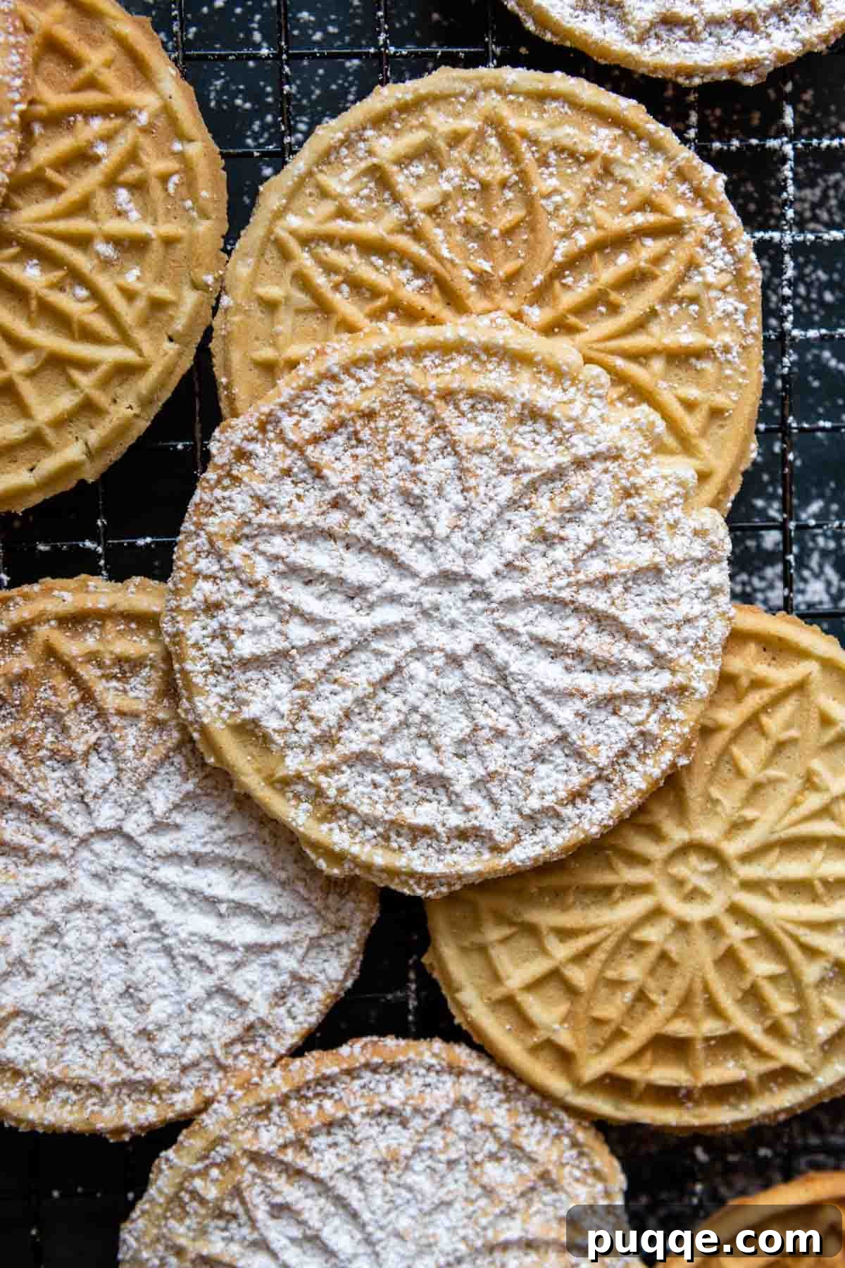 Crispy Gluten-Free Italian Pizzelle Cookies 7 An overhead shot showcasing a beautiful arrangement of freshly baked pizzelles, generously dusted with powdered sugar, cooling on a wire rack.