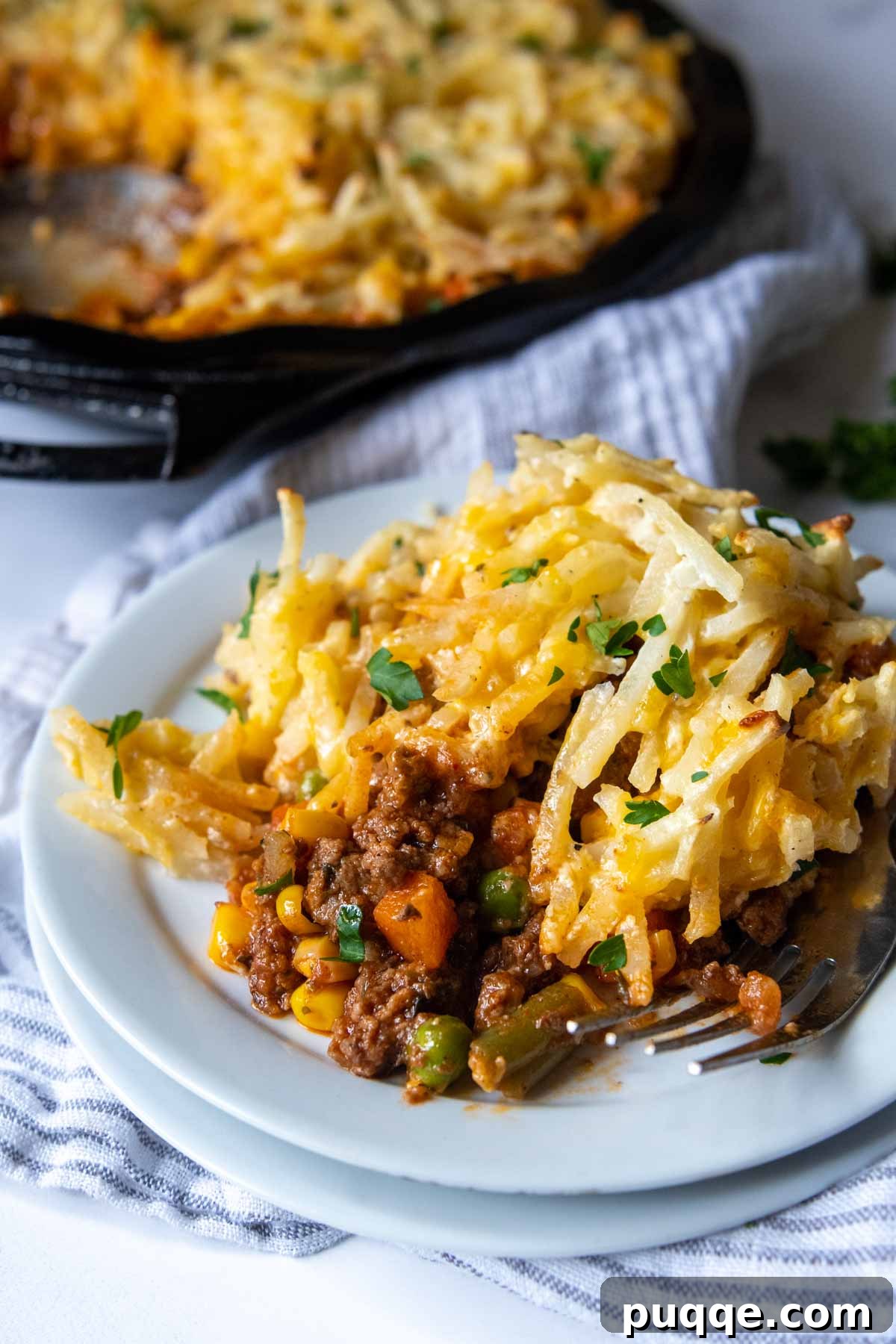 Easy Gluten Free Shepherd Pie 5 a generous serving of cottage pie on a white plate, highlighting the golden hash brown crust.
