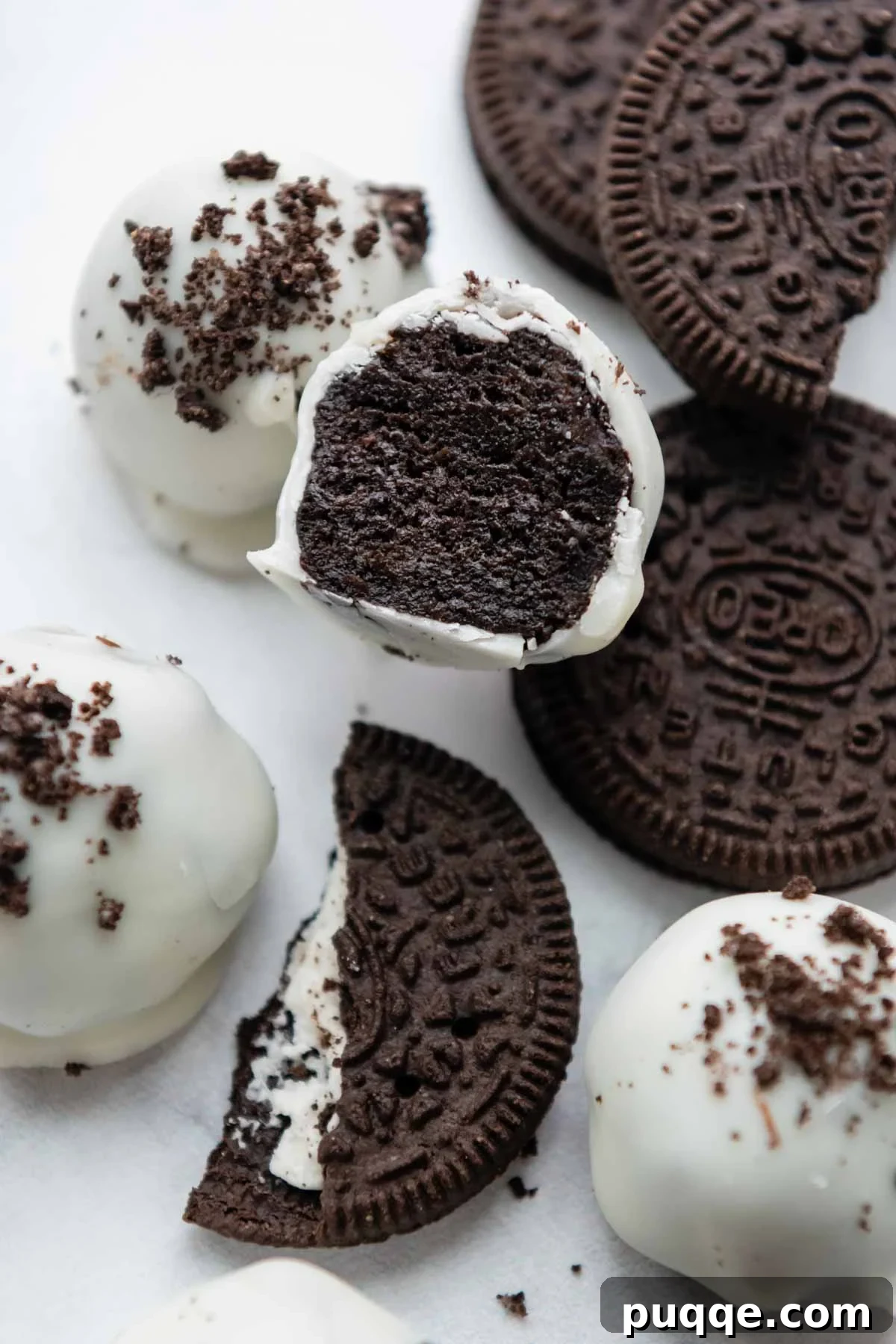 A perfectly halved gluten-free Oreo ball, revealing its rich, creamy center and chocolate coating, positioned centrally against a soft background.