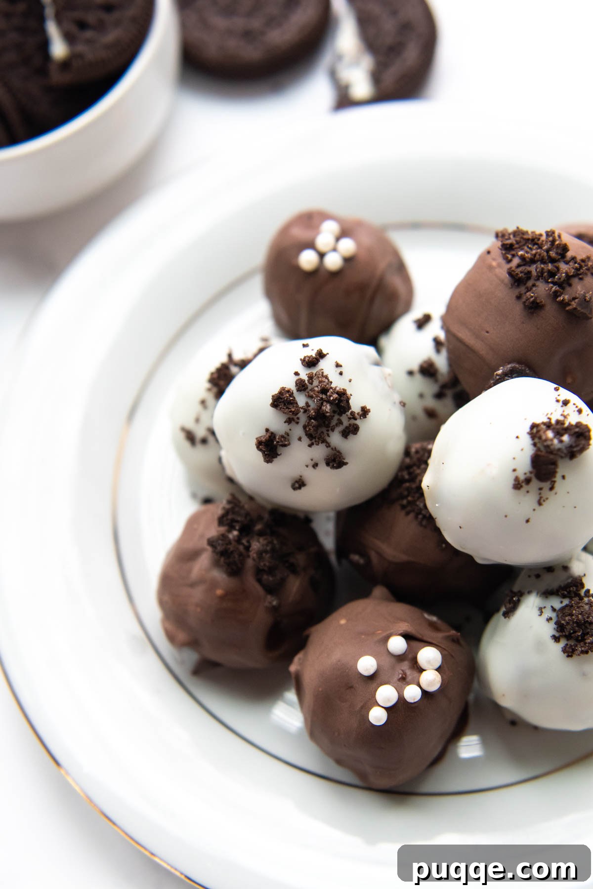 A stunning plate featuring both classic black chocolate and elegant white chocolate truffles, neatly arranged against a clean white backdrop, highlighting their visual appeal.