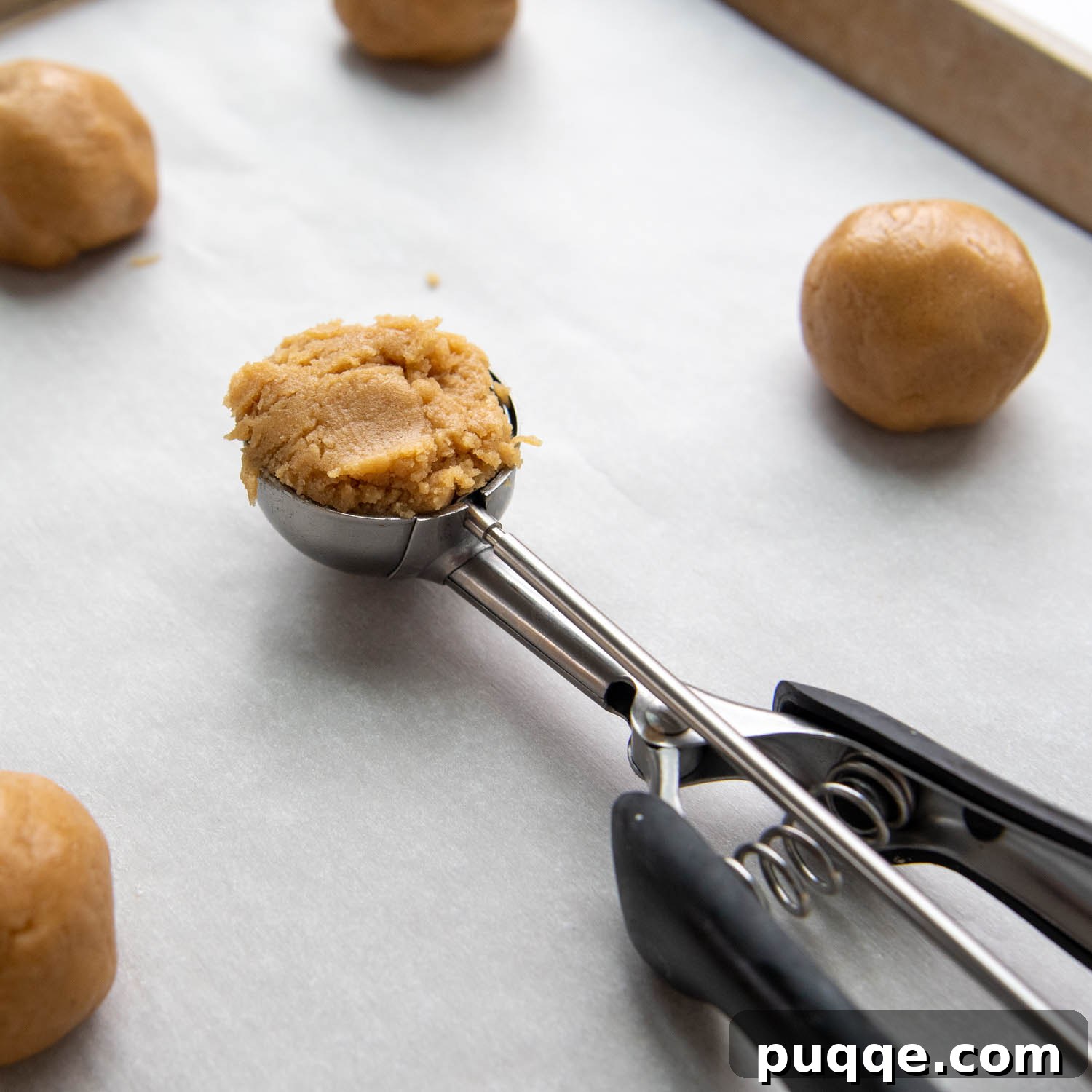 Melt-in-Your-Mouth Gluten-Free Peanut Butter Cookies 5 A cookie scoop full of dough on a baking sheet, ready for baking.