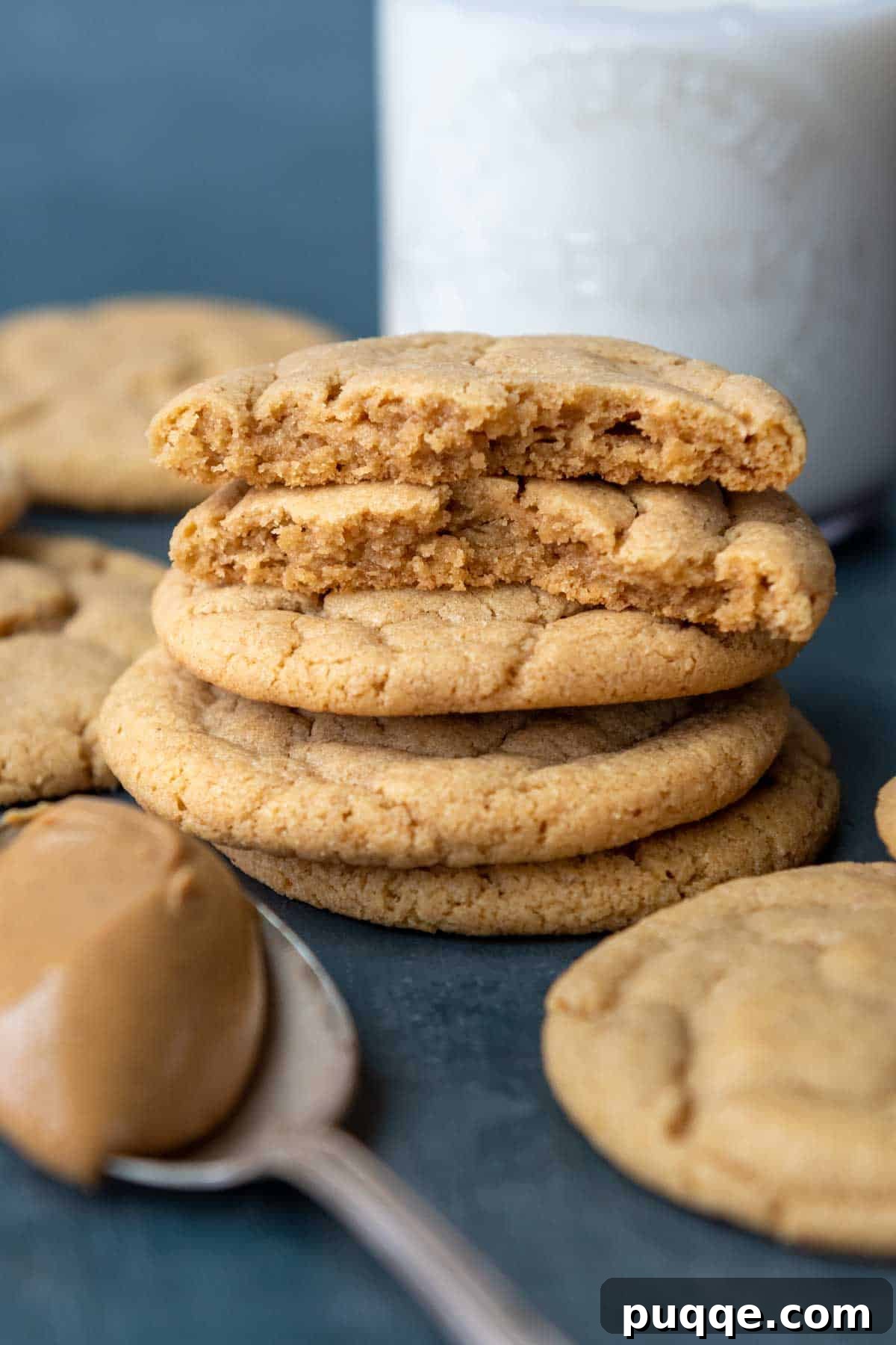 Melt-in-Your-Mouth Gluten-Free Peanut Butter Cookies 6 Two broken gluten-free peanut butter cookies reveal their soft, chewy centers, with a refreshing glass of milk in the background.
