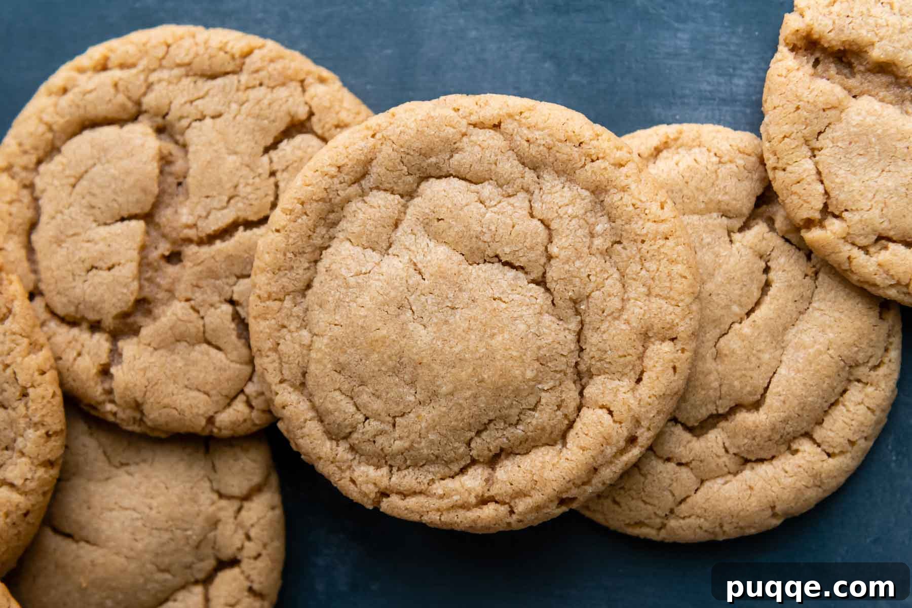 Melt-in-Your-Mouth Gluten-Free Peanut Butter Cookies 7 A perfectly arranged line of golden-brown gluten-free peanut butter cookies against a vibrant blue background.