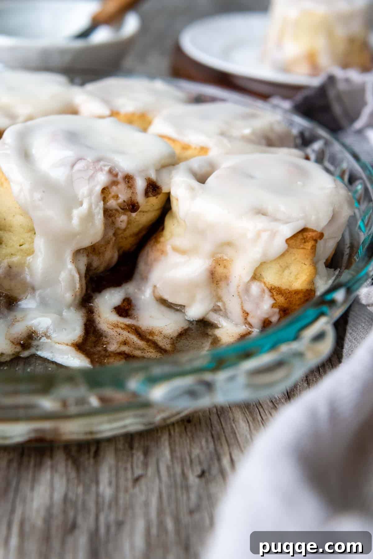 Cloud-Like Gluten-Free Cinnamon Rolls 2 frosted cinnamon rolls in a glass pan, showcasing their soft texture and gooey filling.