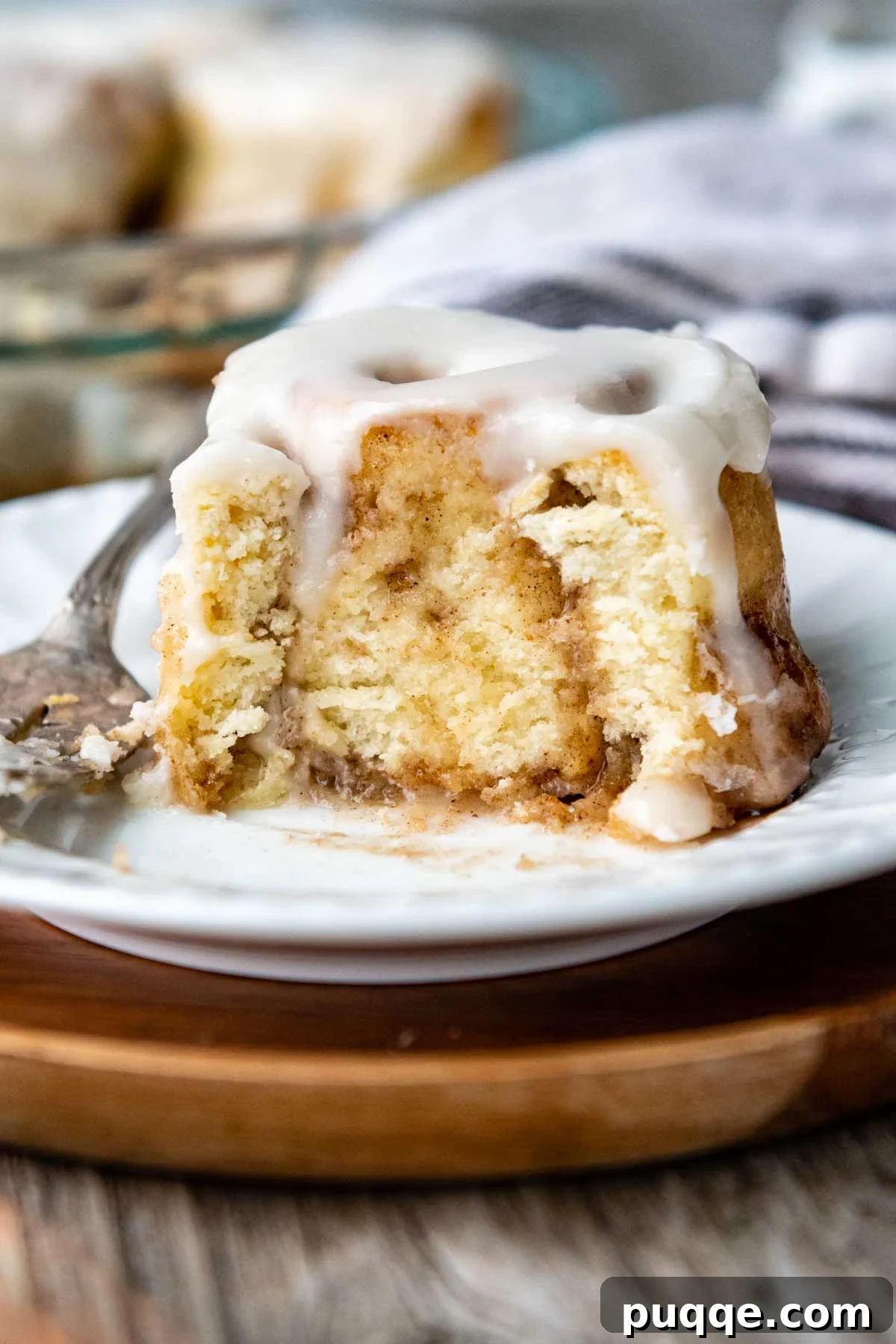 Cloud-Like Gluten-Free Cinnamon Rolls 11 a cinnamon bun with a bite taken out on a white plate, highlighting its soft, doughy texture.