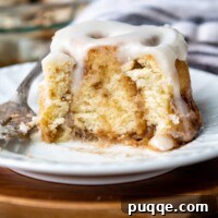Cloud-Like Gluten-Free Cinnamon Rolls 12 A gluten-free cinnamon bun with a bite taken out, resting on a white plate, highlighting its soft texture.