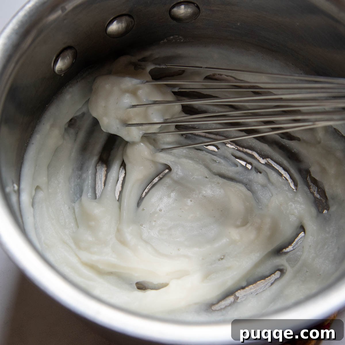 Cloud-Like Gluten-Free Cinnamon Rolls 3 A saucepan containing a thick, smooth roux (flour, water, and milk paste) being prepared on a stovetop.