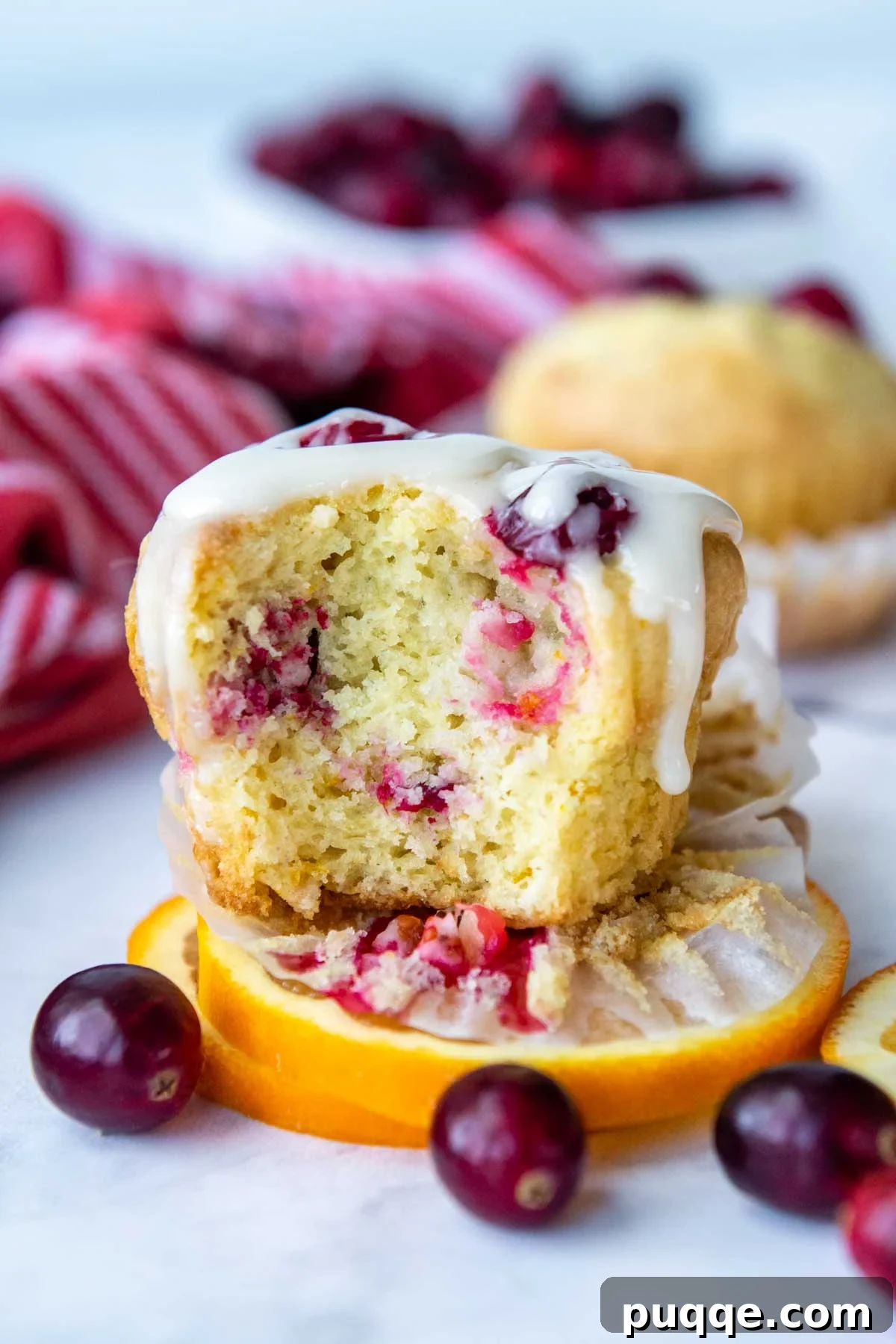 Ultimate Gluten-Free Cranberry Orange Muffins 6 A freshly baked gluten-free cranberry orange muffin, partially eaten, revealing its moist interior and generous orange glaze.