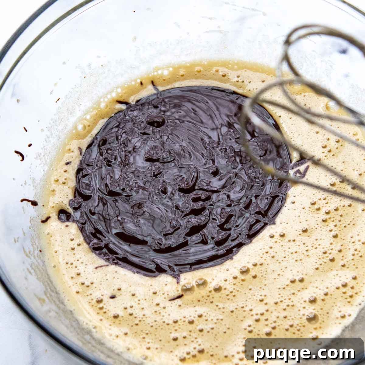 Effortless Gooey Gluten Free Brownie Cookies 4 The smooth, melted chocolate and butter mixture is poured into a bowl containing beaten sugars, eggs, and vanilla, ready for a final blend.
