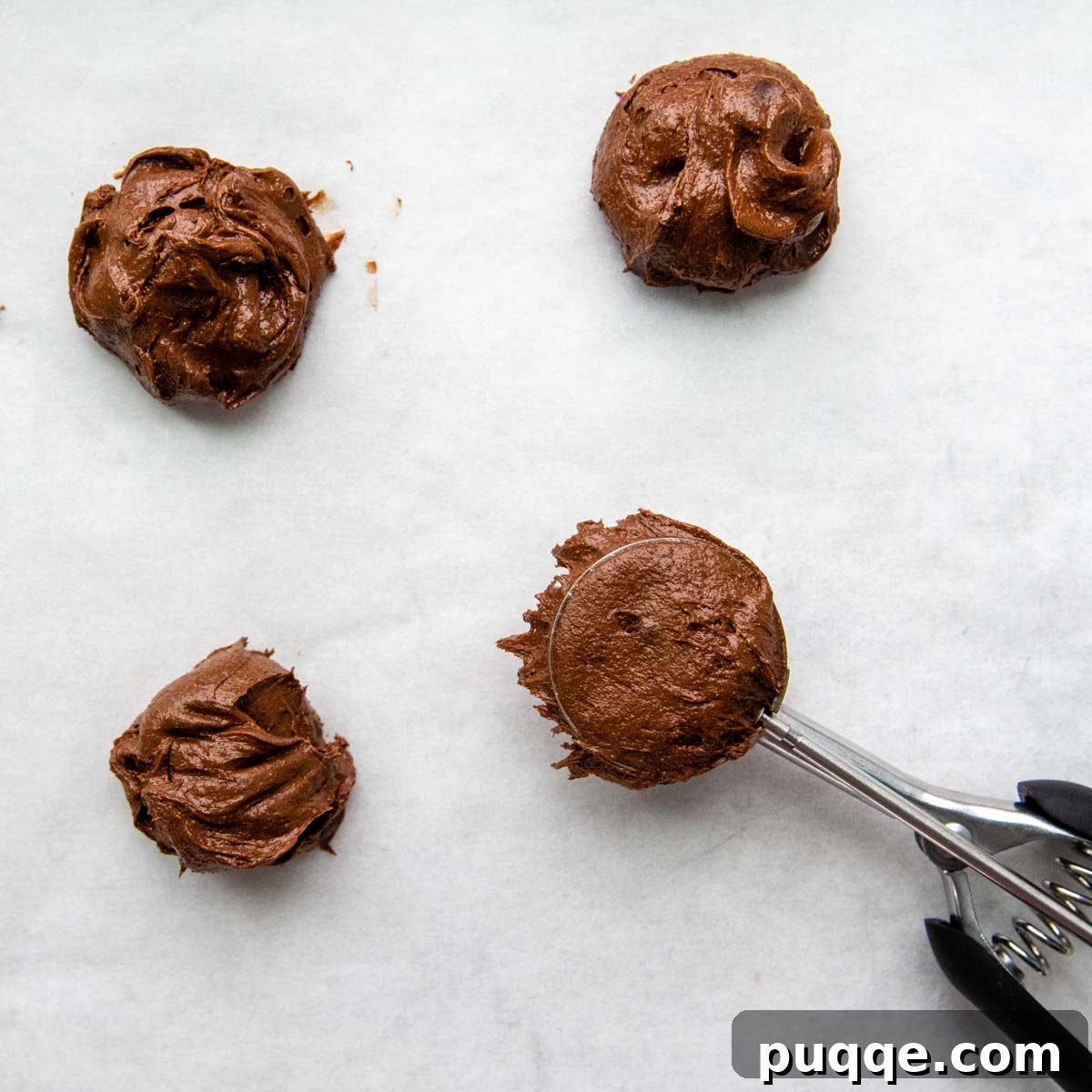 Effortless Gooey Gluten Free Brownie Cookies 6 Unbaked brownie cookie dough balls, perfectly scooped and evenly spaced on a parchment-lined baking sheet, ready for the oven.