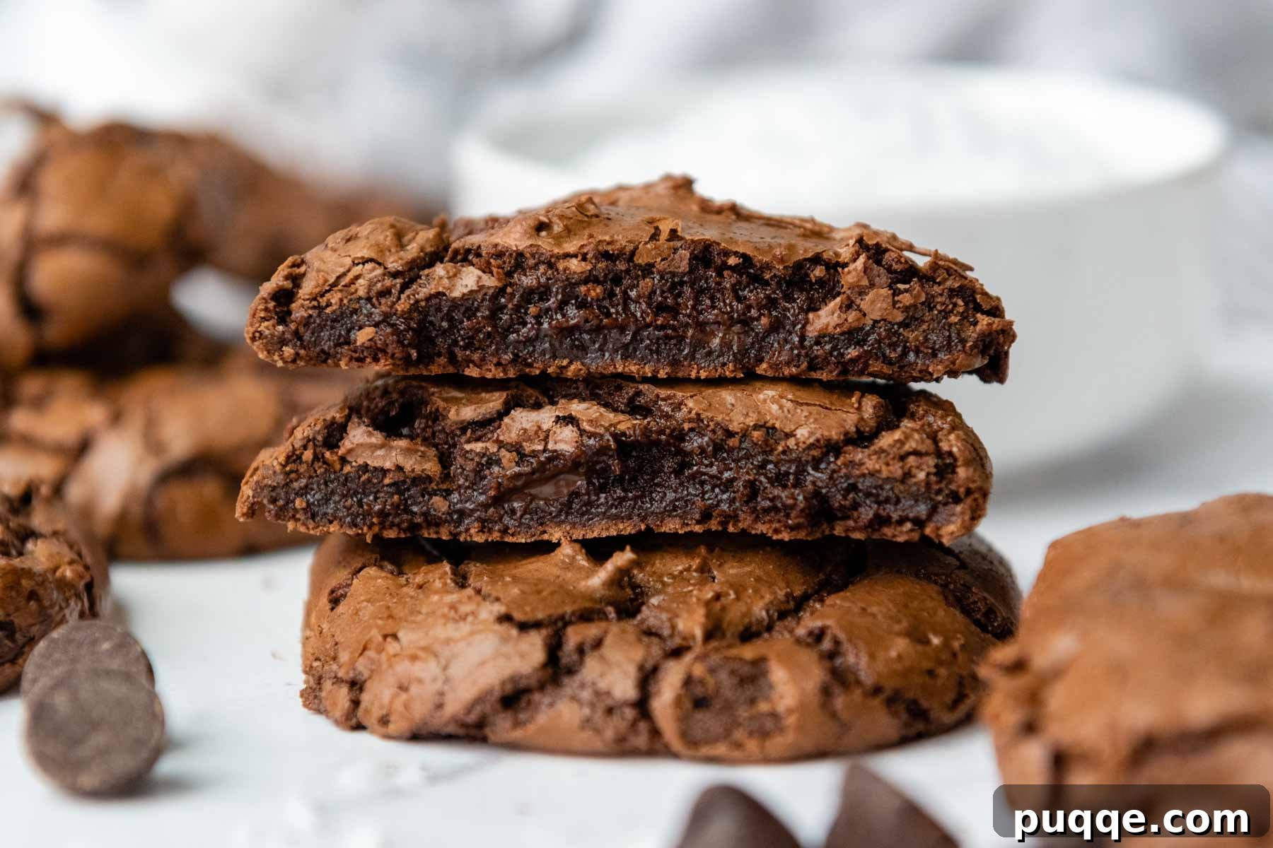 Effortless Gooey Gluten Free Brownie Cookies 8 Two perfectly halved gluten-free brownie cookies are stacked on top of a full, round cookie, showcasing their ultra-fudgy interior and crinkly tops.