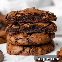A stack of gluten-free chocolate brownie cookies with the top two broken open, revealing their rich, fudgy texture.