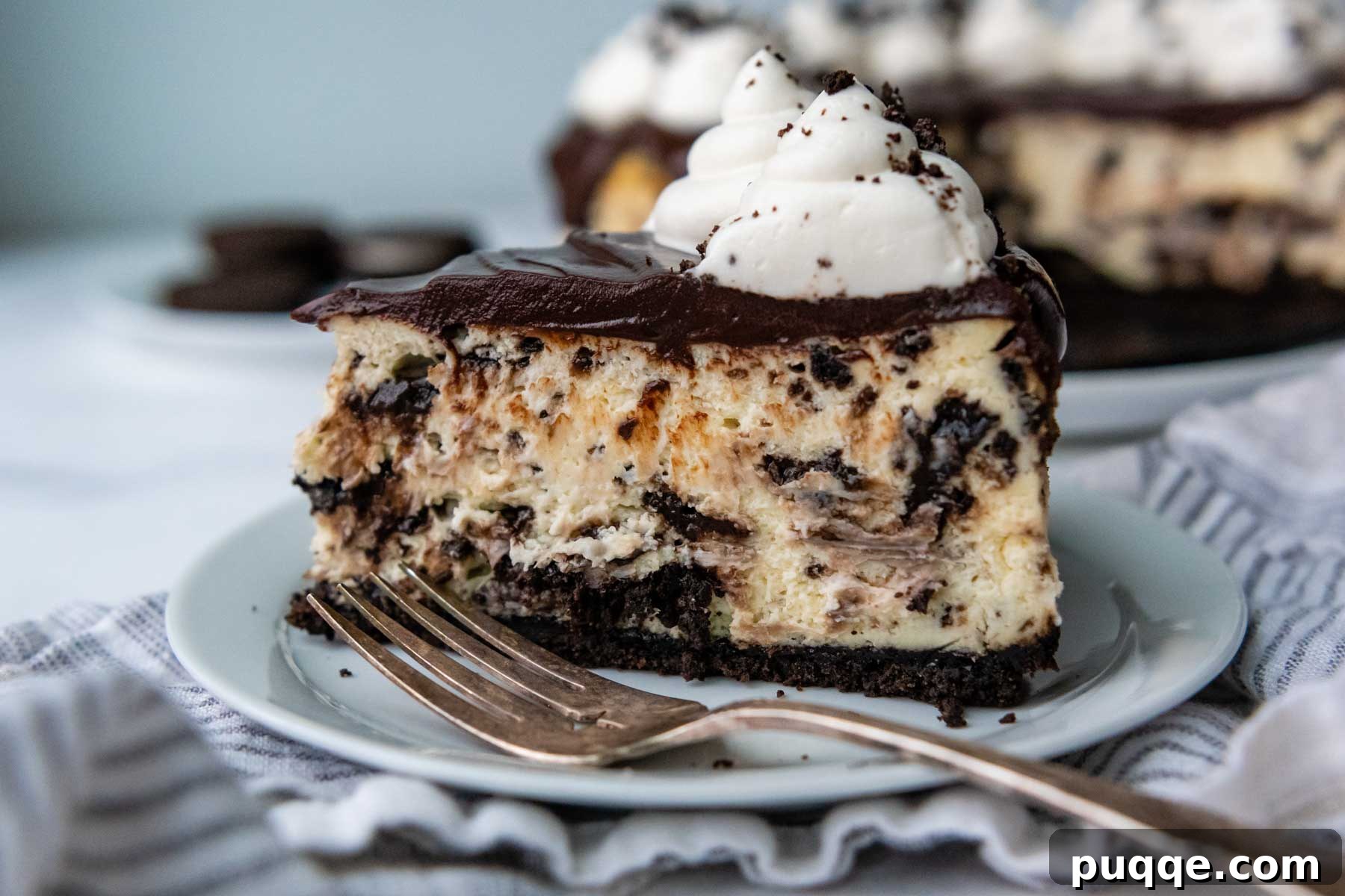 Velvet Smooth Gluten-Free Oreo Cheesecake Bliss 11 A perfect slice of gluten-free Oreo cheesecake, garnished with a dollop of whipped cream and cookie crumbs, on a white plate.