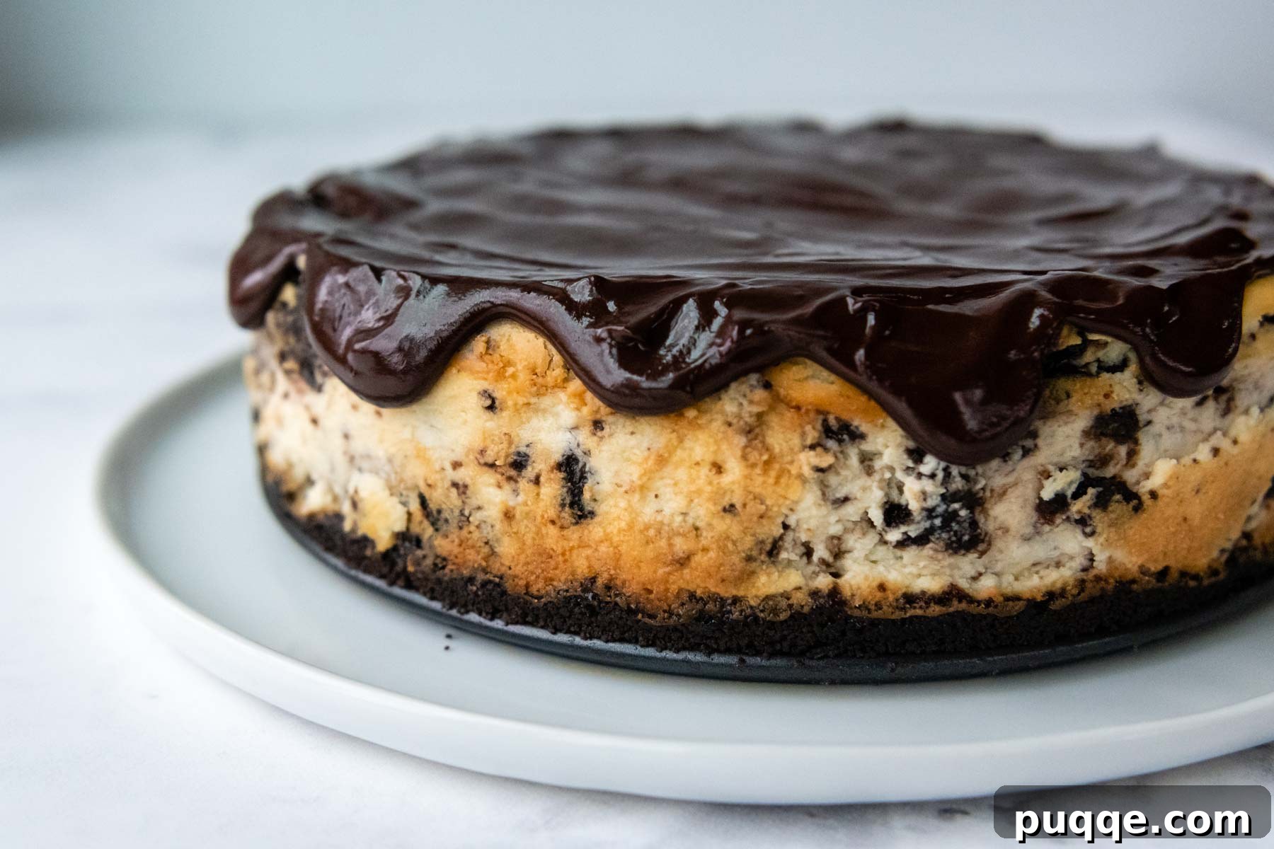 Velvet Smooth Gluten-Free Oreo Cheesecake Bliss 9 Smooth chocolate ganache being spread over a chilled gluten-free Oreo cheesecake.