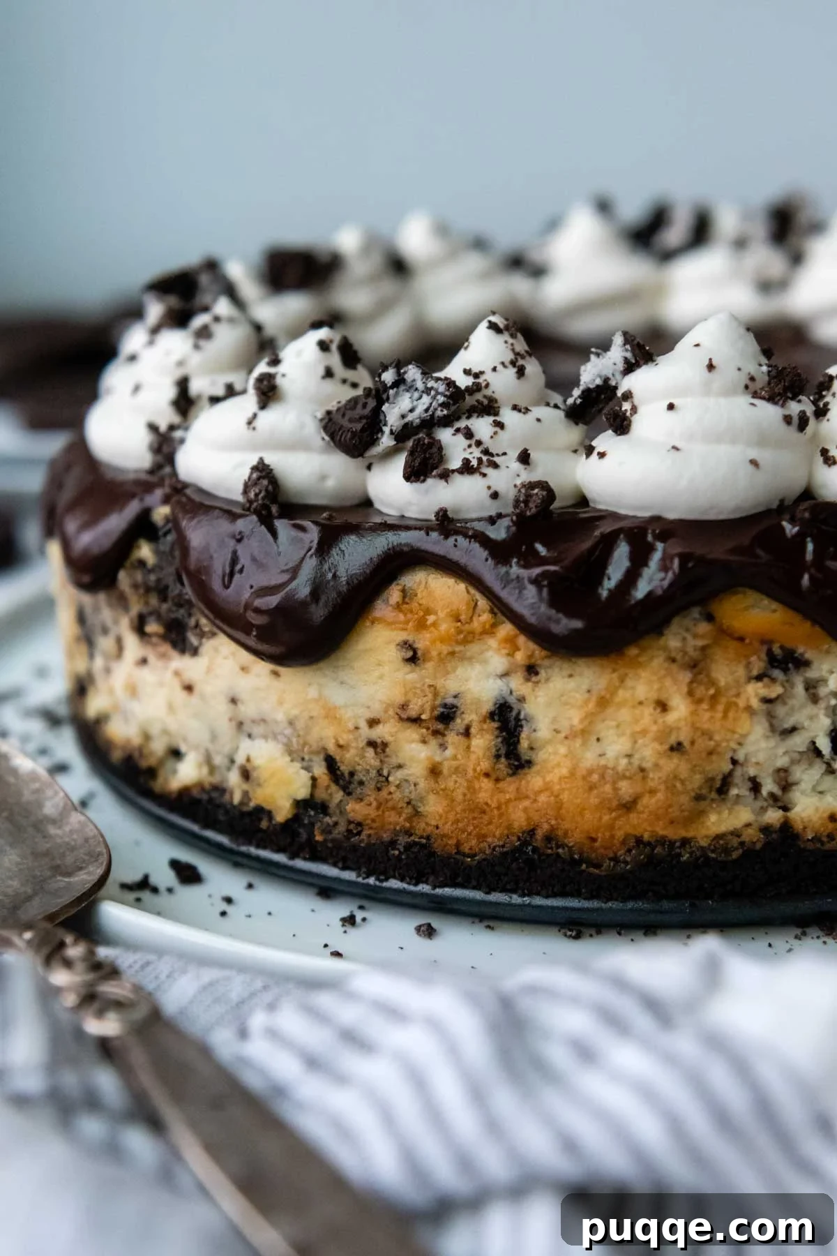 Velvet Smooth Gluten-Free Oreo Cheesecake Bliss 10 An exquisitely decorated gluten-free Oreo cheesecake, uncut, adorned with chocolate ganache, whipped cream swirls, and crushed Oreo crumbs.