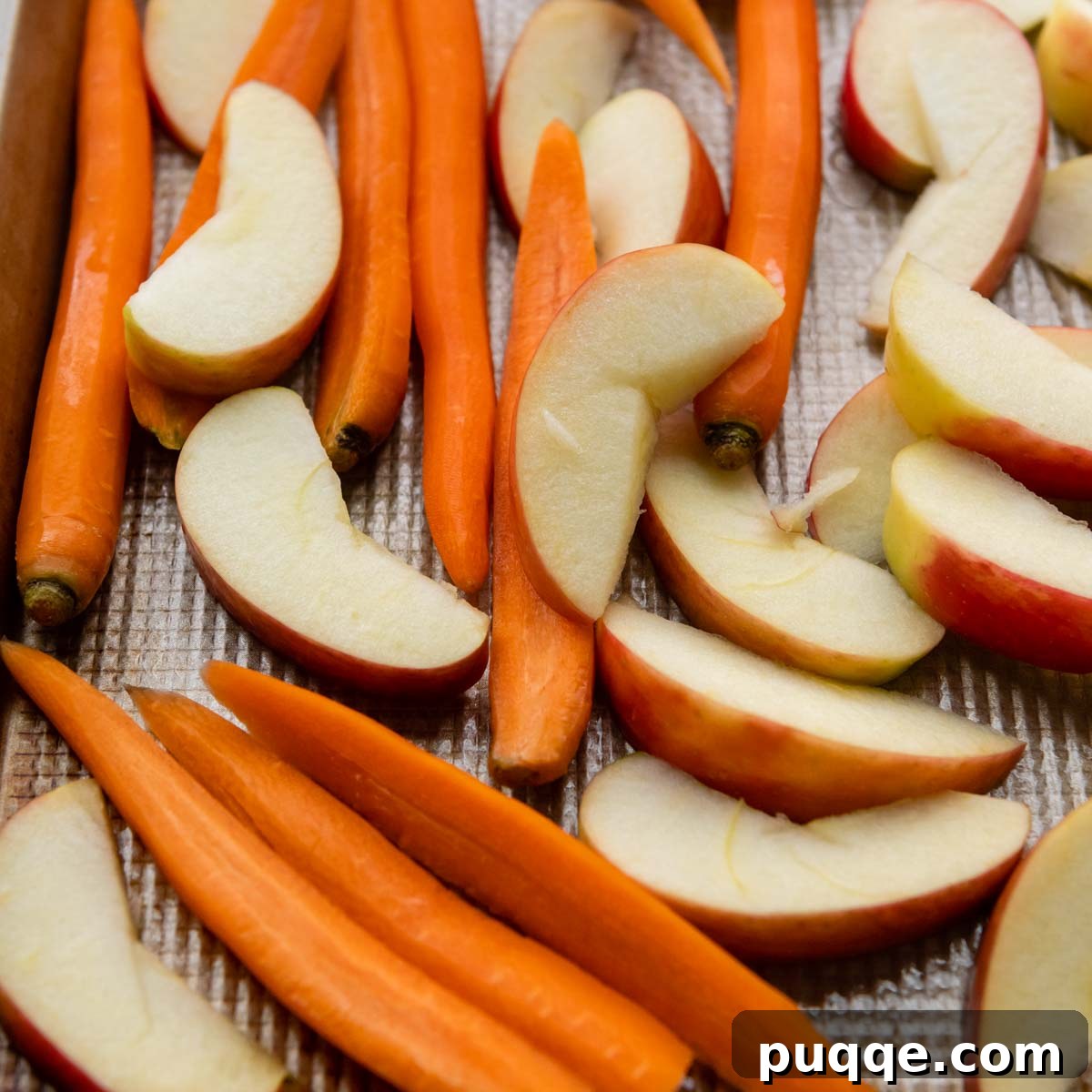 Roasted Carrots and Apples with Maple Dijon Glaze 3 Raw, cut carrots and apple slices arranged neatly on a baking pan before roasting, showcasing uniform preparation.