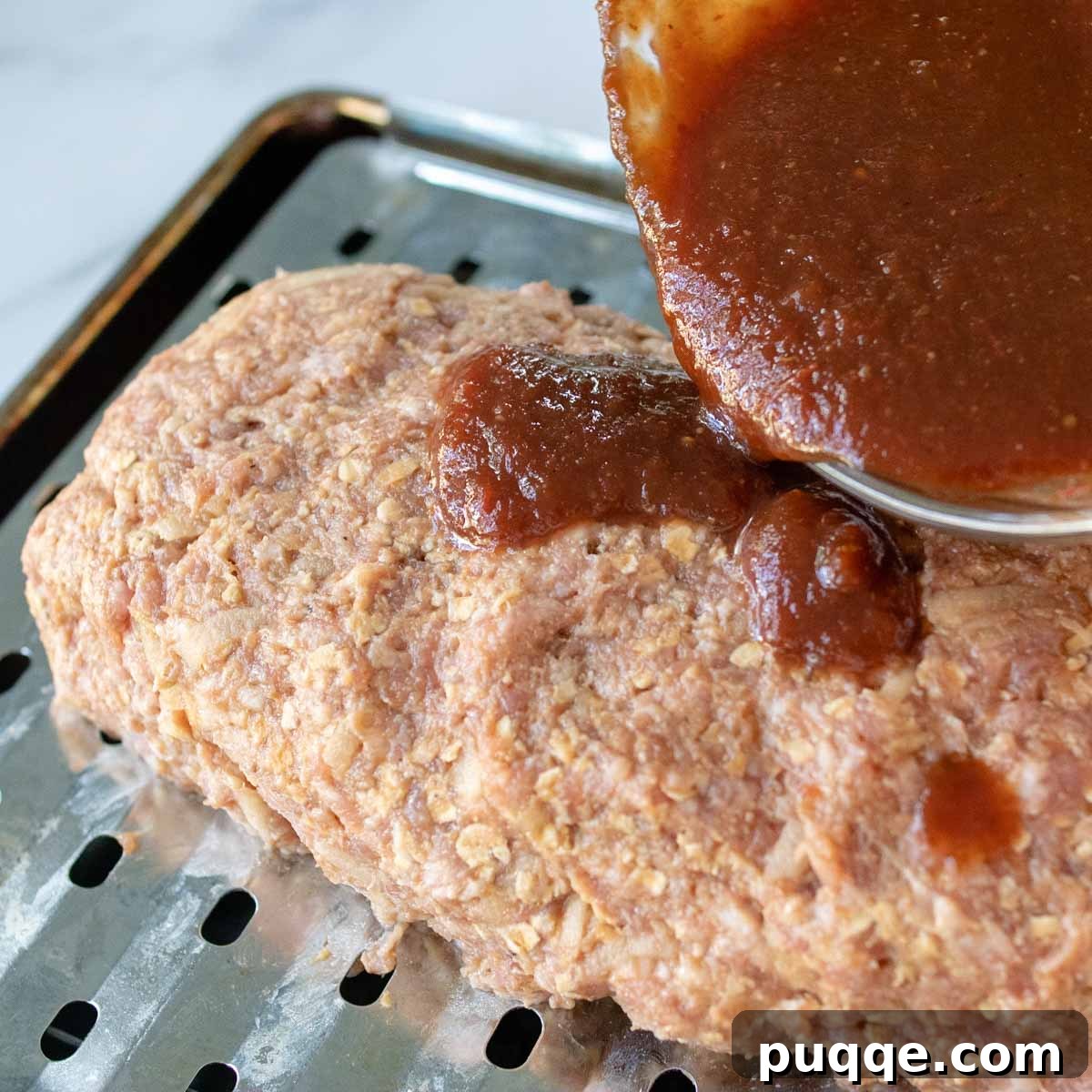 Tangy sweet glaze being poured over the shaped pork meatloaf.