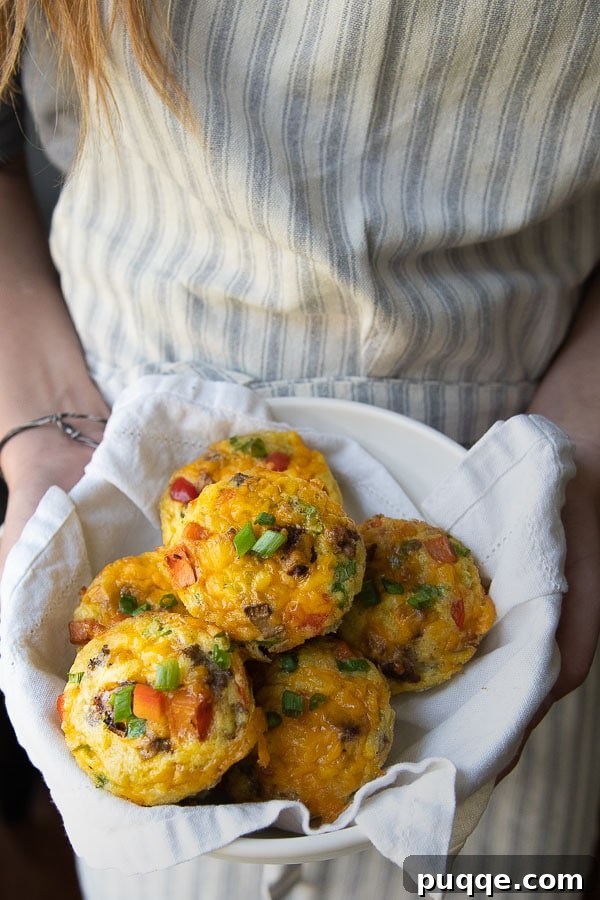 Someone holding a bowl filled with freshly baked breakfast egg muffins, ready to be served and enjoyed.