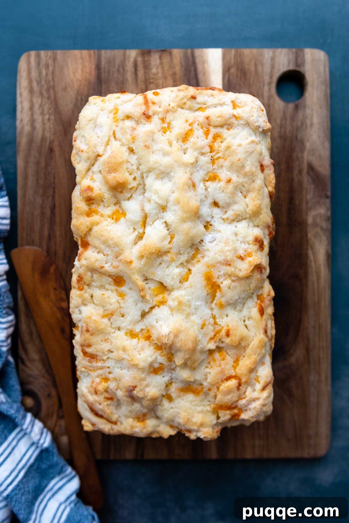Quick Cheesy Gluten Free Beer Bread 6 an uncut loaf of bread on a wooden cutting board.