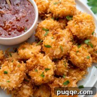 Golden Guilt-Free Coconut Shrimp: Oven or Air Fryer Crisp 8 A plate of gluten-free coconut shrimp with a dipping sauce next to it.
