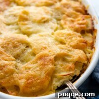 A spoon going into baked au gratin potatoes, showing the creamy, cheesy layers.