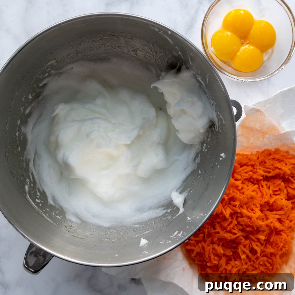Cloud-Like Gluten-Free Almond Flour Carrot Cake 3 Grated carrots, separated egg whites in a bowl, and egg yolks in another bowl.