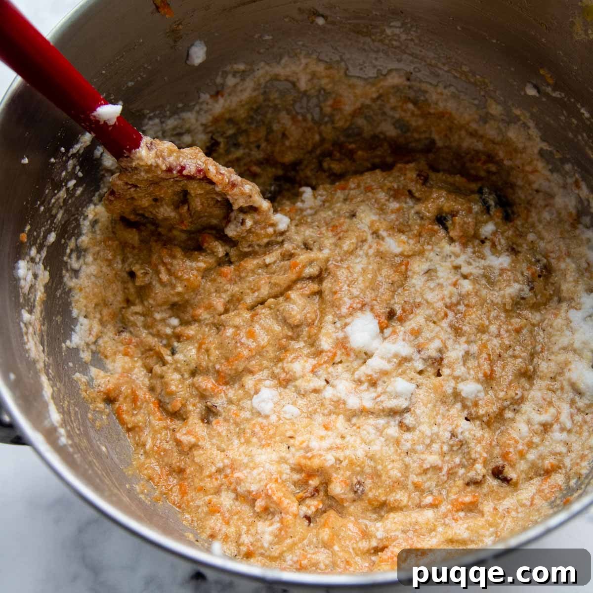 Cloud-Like Gluten-Free Almond Flour Carrot Cake 7 A spoon gently folding in beaten egg whites into the cake batter.