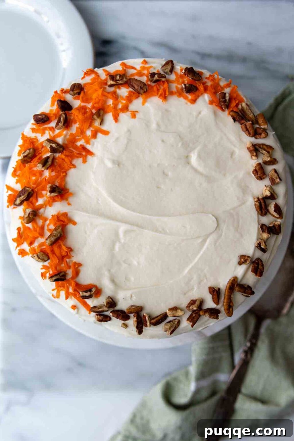 Cloud-Like Gluten-Free Almond Flour Carrot Cake 8 Top of a frosted carrot cake decorated with grated carrots and chopped nuts.