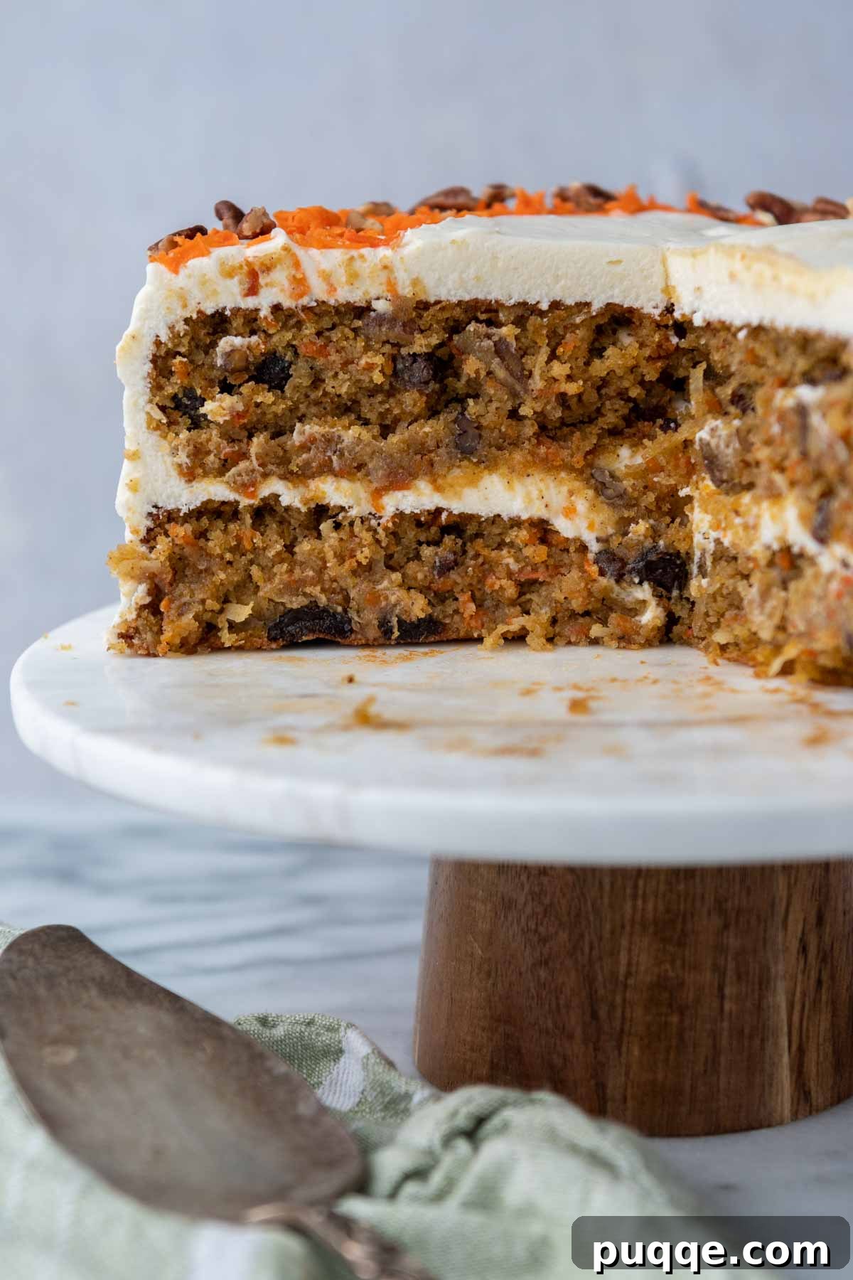 Cloud-Like Gluten-Free Almond Flour Carrot Cake 9 A beautifully layered carrot cake on a cake stand with a large slice missing, revealing the moist layers and frosting.