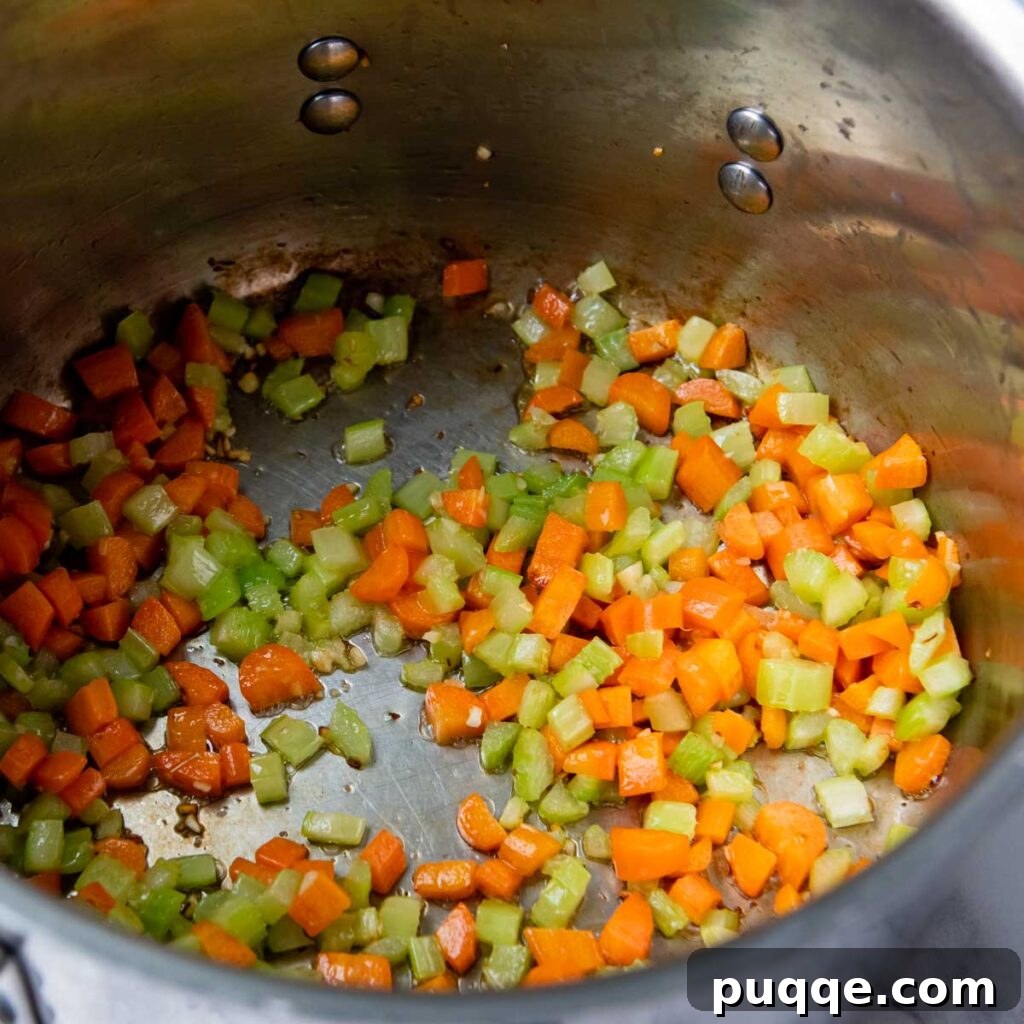 Effortlessly Flavorful Gluten-Free Chicken Noodle Soup 3 Sautéing diced carrots, celery, and minced garlic in melted butter to build the flavor base for the soup.