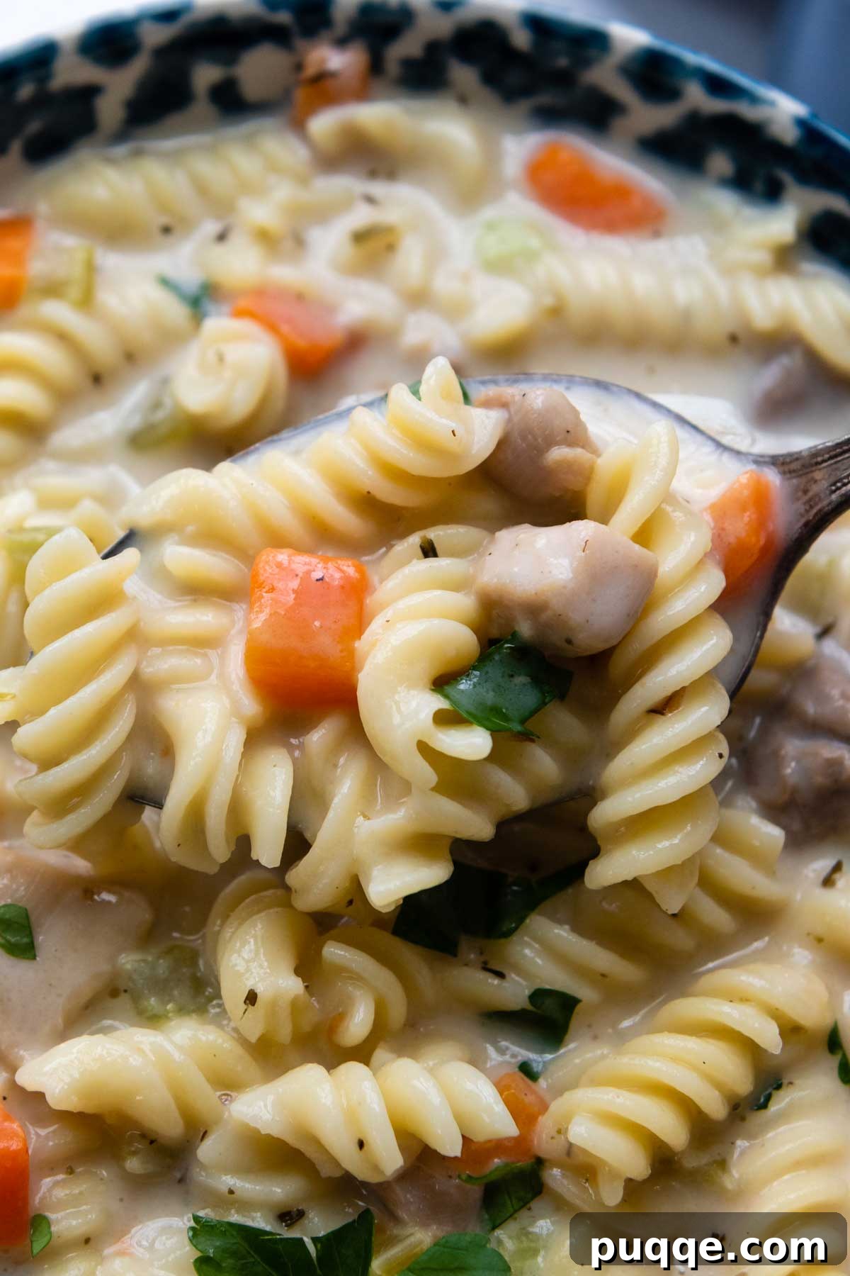 Effortlessly Flavorful Gluten-Free Chicken Noodle Soup 8 A close-up shot of a spoonful of creamy gluten-free chicken noodle soup, showing tender chicken, soft noodles, and vibrant vegetables.