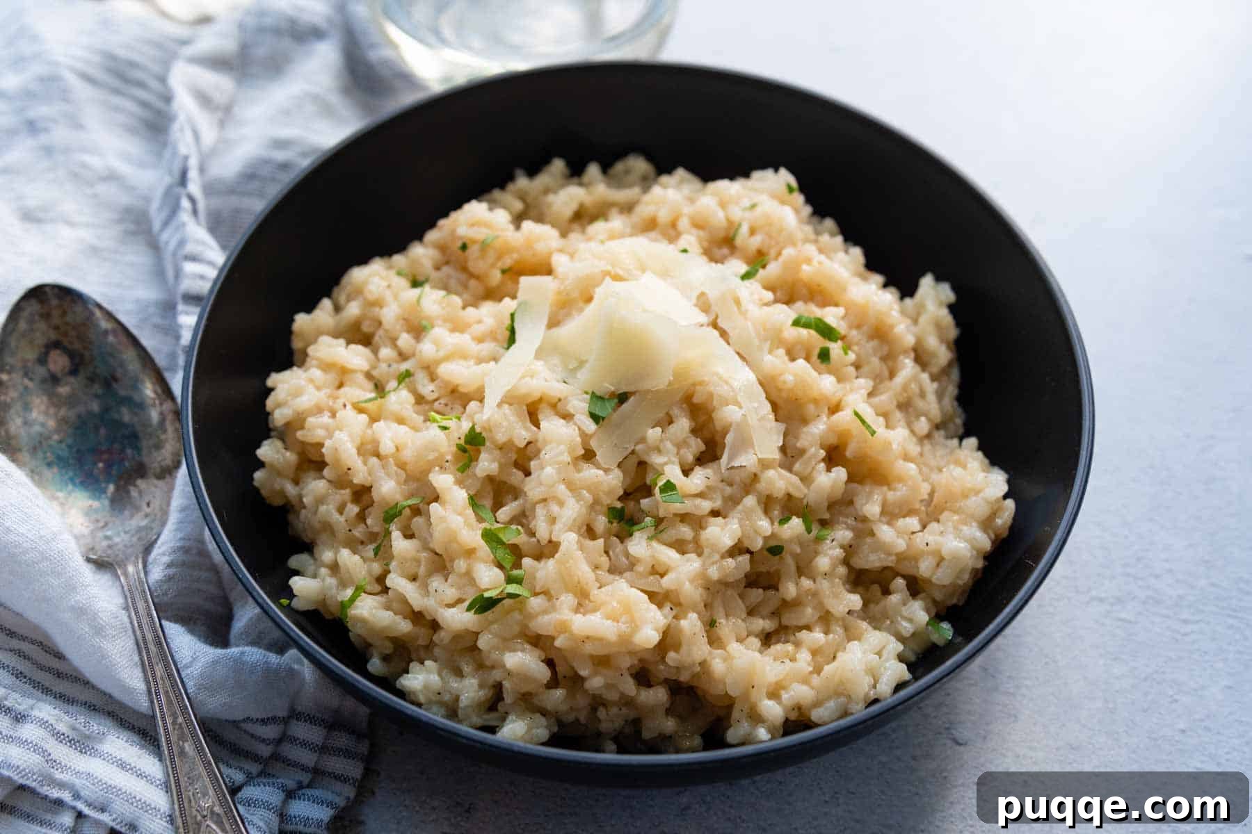 risotto in a black bowl with fresh parmesan on top.