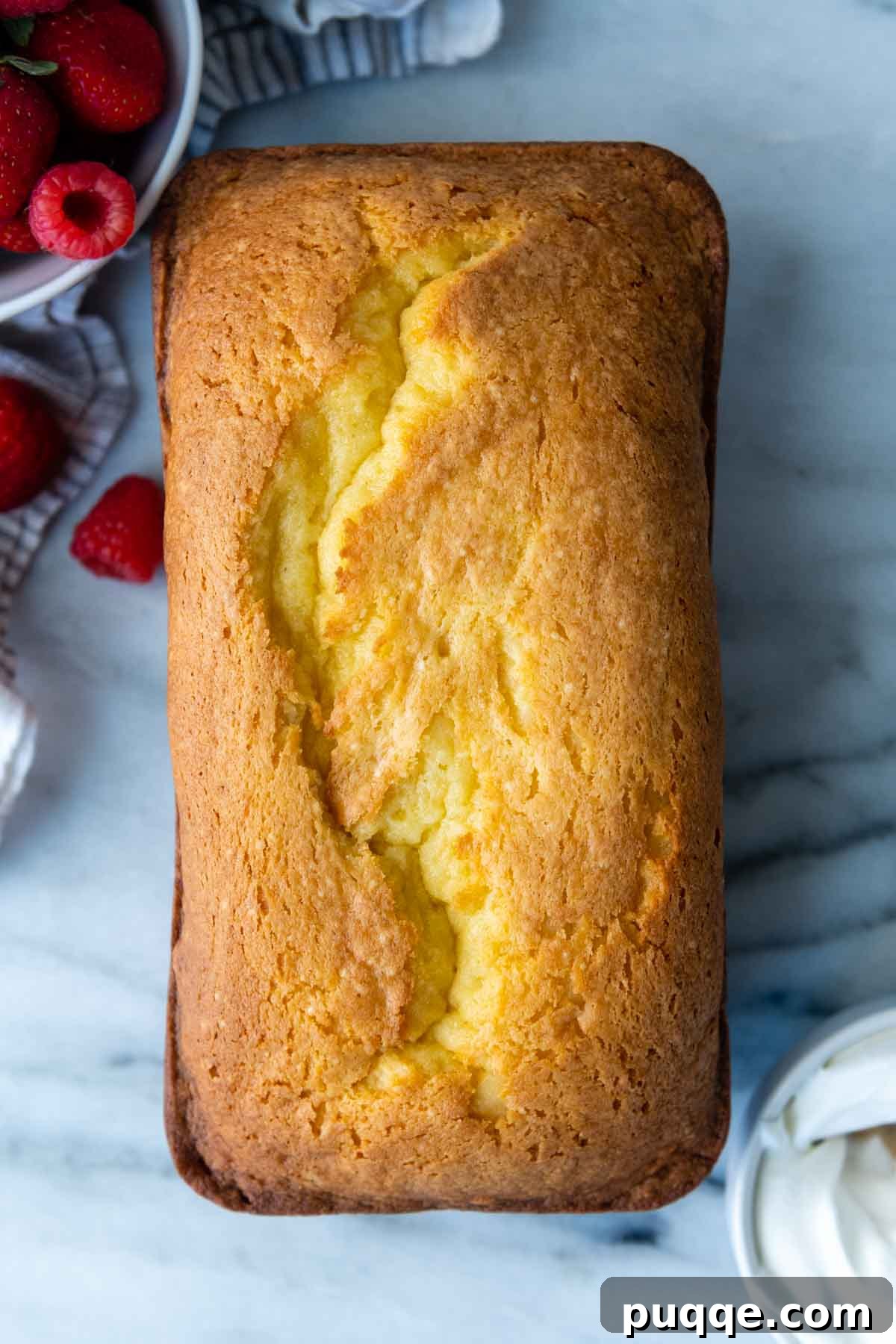 The Secret to Unbelievably Moist Gluten-Free Pound Cake 7 A pristine, uncut gluten-free loaf cake resting elegantly on a polished marble slab, showcasing its golden crust.