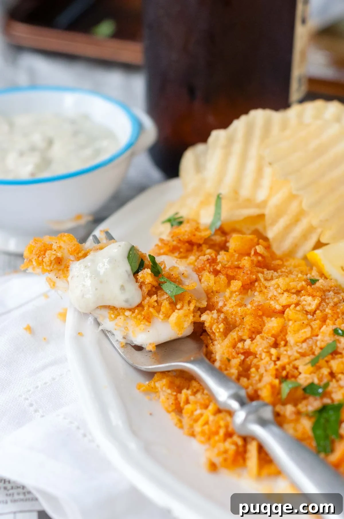 a fork with a bite of fish and tartar sauce on top.