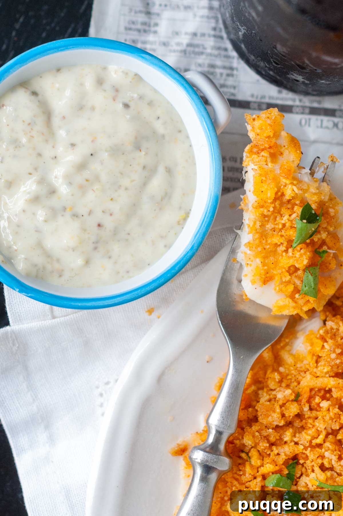 overhead shot of a small bowl of tartar sauce with a bite of fish next to it.