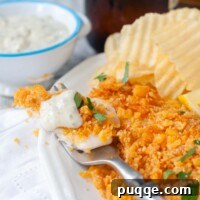 a fork with a bite of fish and tartar sauce on top.