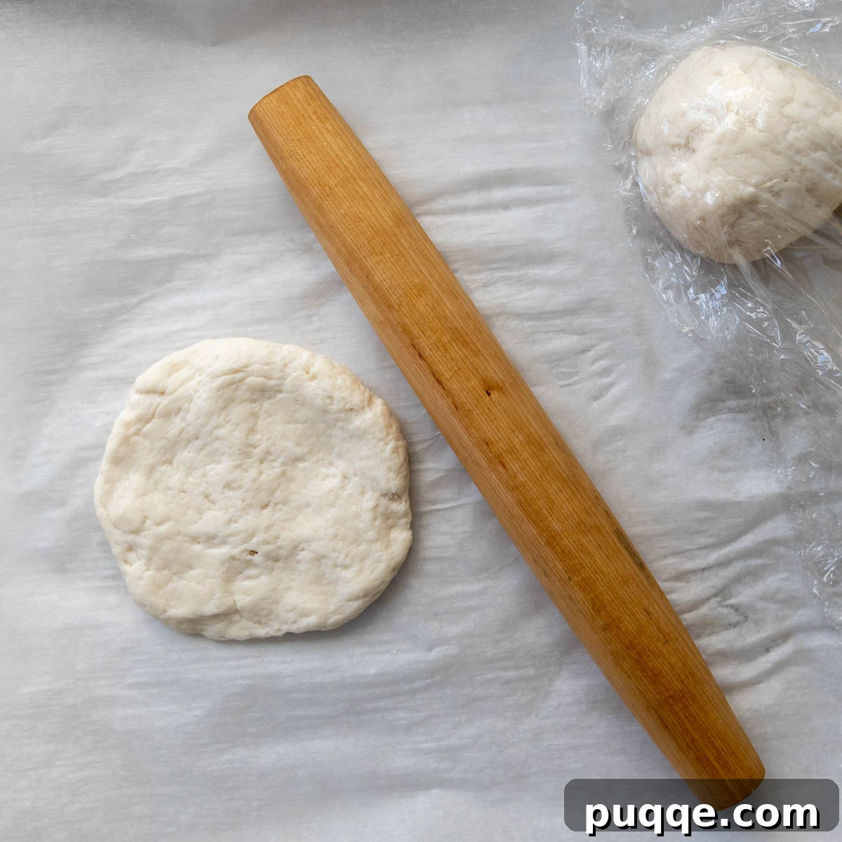 Foolproof Soft Gluten-Free Flatbread 6 A ball of gluten-free dough flattened into a thick disc on parchment paper, ready for rolling.