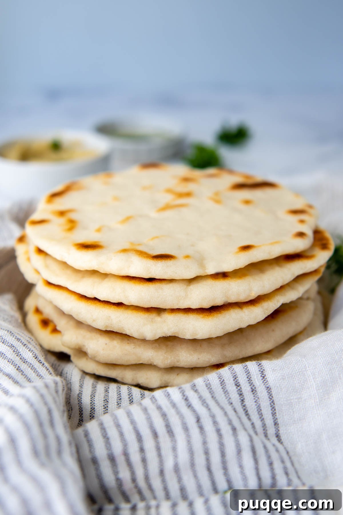 Foolproof Soft Gluten-Free Flatbread 8 A beautiful stack of freshly cooked gluten-free flatbreads resting on a white kitchen towel, ready to be served.