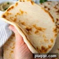 A soft gluten-free flatbread being folded, highlighting its flexibility.
