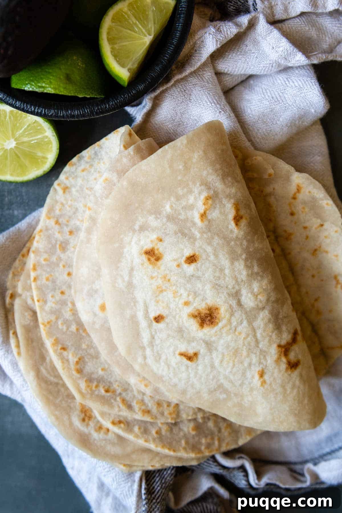 Freshly cooked gluten-free tortillas, folded and garnished with a lime wedge.