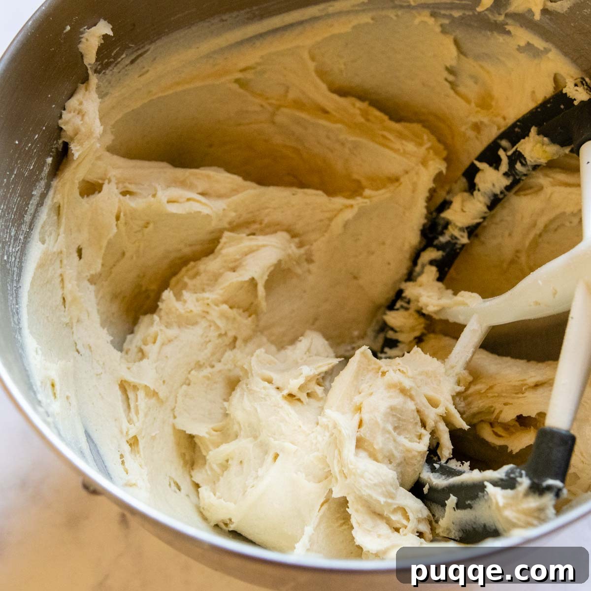 Close-up of the sticky, well-mixed gluten-free hot dog bun dough in a stand mixer bowl.